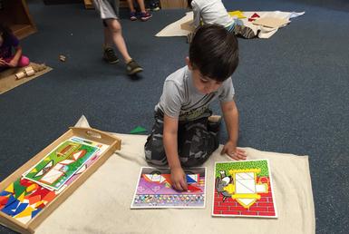 A boy working on a puzzle on a classroom rug
